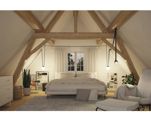 Gemütliches Schlafzimmer im Dachgeschoss mit Holzbalken, Bett und Beleuchtung.