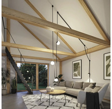 Wohnzimmer mit Dachschrägen, Balken, Treppe, Sofa, Teppich und Pendelleuchten.