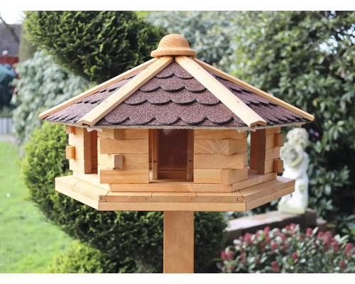 Vogelhaus aus Holz mit braunem Dach auf einem Pfosten