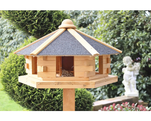 Vogelhaus aus Holz mit Dach auf einem Pfosten im Garten.