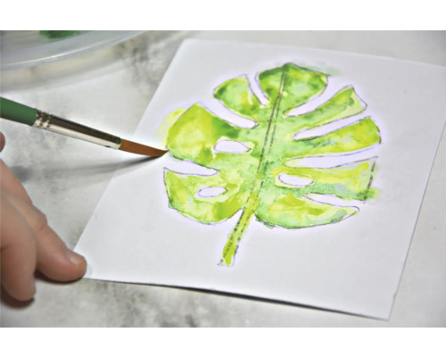 Aquarellmalerei eines Monstera Blattes mit Pinsel auf Papier