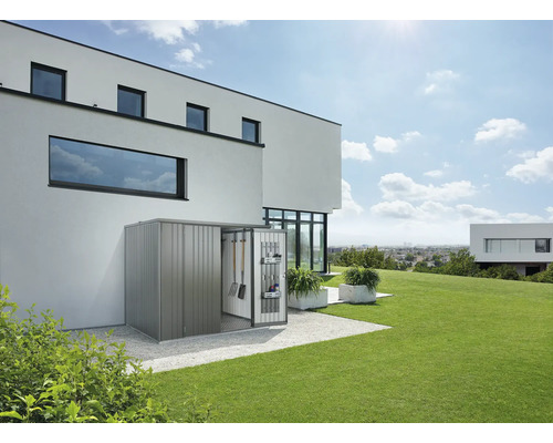 Metall Gerätehaus mit geöffneter Tür und Gartengeräten vor modernem Haus