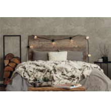 Dekoratives Schlafzimmer mit Holzkopfende, Lichterkette, Kissen und Tagesdecke
