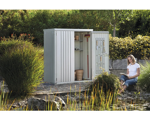 Metall Gartenhaus mit Regalen und Werkzeugen im Garten mit lesender Frau