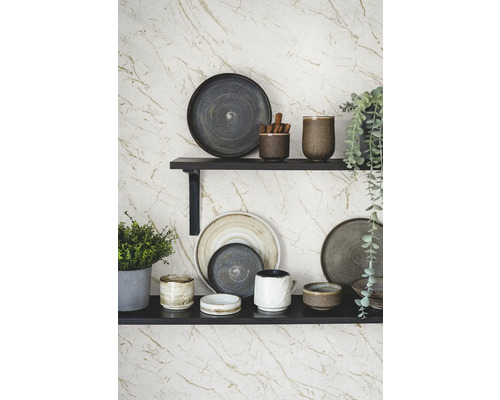 Dekorative Teller und Tassen auf Regalen an einer gemusterten Wand