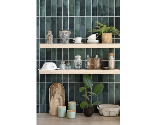 Dekorative Küchenszene mit Regalen, Geschirr und Pflanzen vor grünen Wandfliesen.