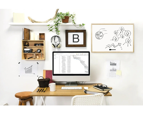 Arbeitszimmer mit Schreibtisch, Computer, Whiteboard und Dekorationsgegenständen für eine organisierte und helle Atmosphäre