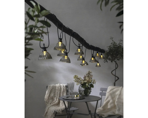 Dekorative Lichterkette mit mehreren Lampen über einem Tisch mit Stühlen