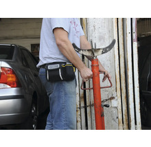 Eine Person mit einer Werkzeugtasche der Marke Stanley und einer Getriebestütze.
