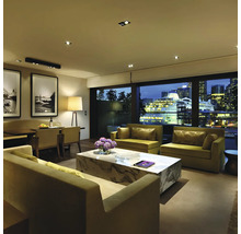 Wohnzimmer mit Sofas, Marmortisch und Blick auf die Stadt bei Nacht.