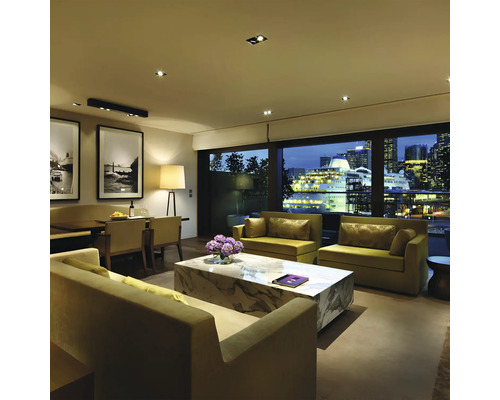 Wohnzimmer mit Sofas, Marmortisch und Blick auf die Stadt bei Nacht.