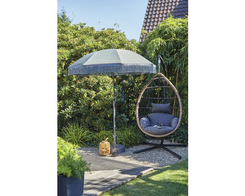 Gartenszene mit Sonnenschirm, Hängekorbsessel und Dekoration