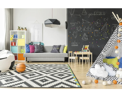 Helles Kinderzimmer mit Sofa, Spielzeug, Teppich und Tafelwand