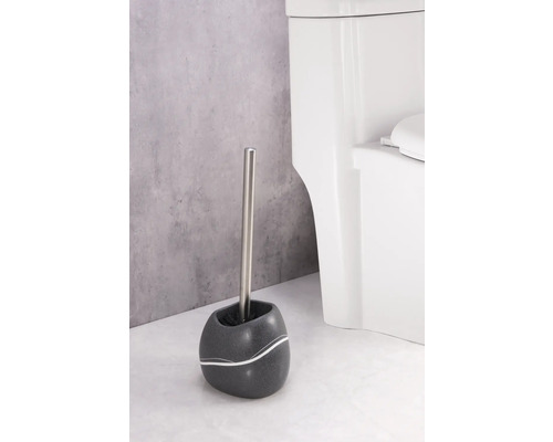 Toilettenbürste mit Halter und WC im Hintergrund