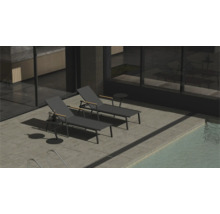 Zwei Liegestühle und ein Beistelltisch neben einem Pool