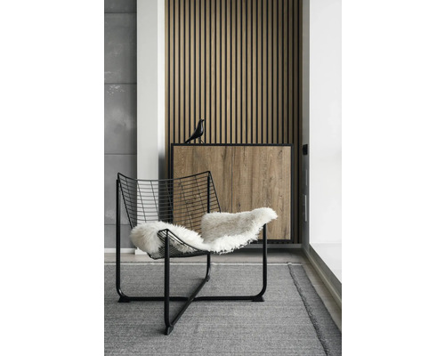 Innenraumszene mit einem Sessel mit Fell, einem Schrank mit Holzdekor und einer dekorativen Vogelstatue.