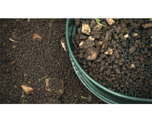 Erde wird durch ein Gartensieb gesiebt