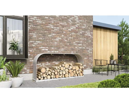 Holzlager aus Metall gefüllt mit Brennholz vor einer Backsteinmauer