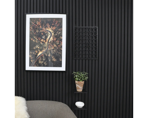 Dekorative Wandgestaltung mit geriffelten Paneelen, einem gerahmten Bild, einem geometrischen Gitter, einer Topfpflanze und einem kleinen Regal