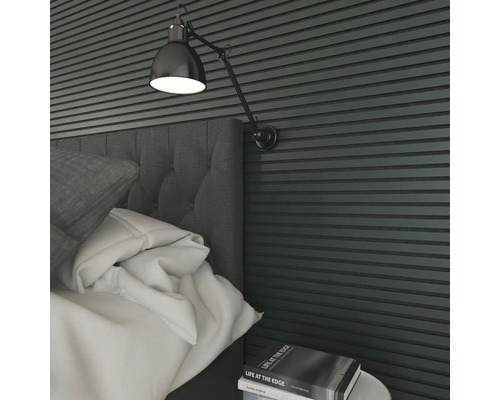 Nahaufnahme eines Schlafzimmers mit Bett, Nachttisch, Buch und Wandleuchte