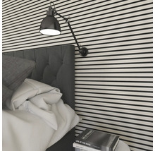 Schlafzimmer mit Bett, Nachttischlampe und gestreifter Wand