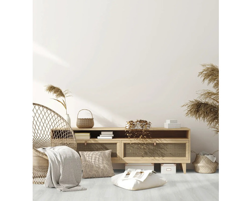 Wohnzimmer mit Rattansessel, Kommode, Kissen und dekorativen Elementen für eine gemütliche Atmosphäre.