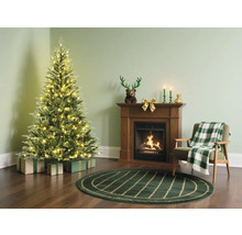 Weihnachtsszene mit Tannenbaum, Kamin und Sessel in einem gemütlichen Wohnzimmer