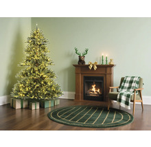 Weihnachtszimmer mit beleuchtetem Weihnachtsbaum, Kamin und Sessel