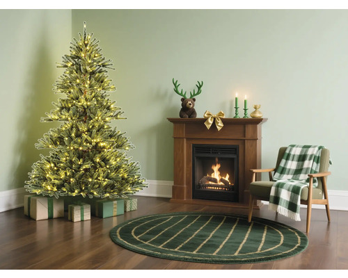 Weihnachtszimmer mit beleuchtetem Weihnachtsbaum, Kamin und Sessel