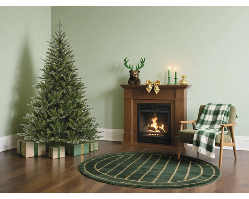 Wohnzimmer mit Weihnachtsbaum, Kamin und Sessel für festliche Atmosphäre