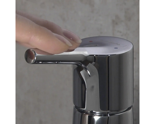 Nahaufnahme eines verchromten Wasserhahns mit Hand, die den Hebel betätigt