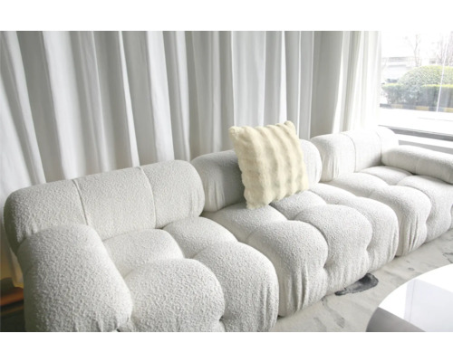 Großes Sofa mit weichem Kissen vor einem Fenster mit Vorhängen