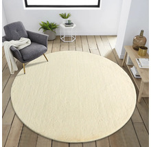 Wohnzimmer mit rundem Teppich, Sessel und Beistelltisch auf Holzboden