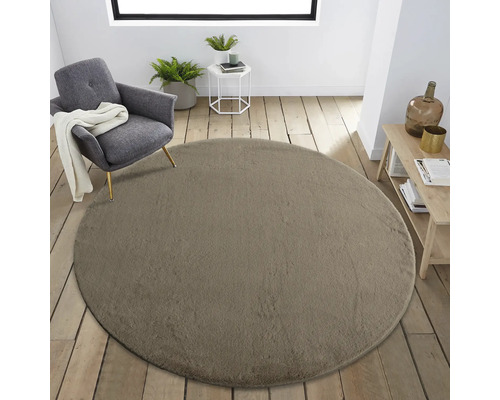 Raumansicht mit rundem Teppich, Sessel und Beistelltisch