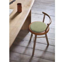 Holzhocker mit rundem Sitzkissen und Rückenlehne neben einem Tisch.