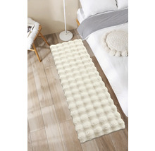 Flauschiger Teppich im Schlafzimmer neben einem Bett und einer Lampe.