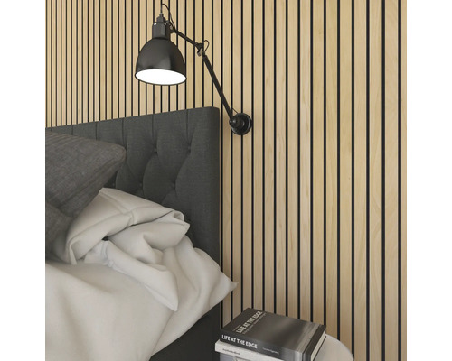 Schlafzimmer mit Akustikpaneelen an der Wand und einer verstellbaren Wandleuchte über dem Bett