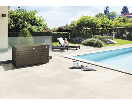 Szene im Freien mit einer Aufbewahrungsbox neben einem Pool, Liegestühlen und Garten.