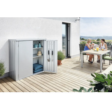 Gartenschrank aus Metall mit geöffneter Tür auf einer Terrasse, darin Gartengeräte und Dekoration