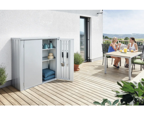 Terrassenschrank Biohort Romeo L High 132 x 87 x 181 cm silber-metallic Gartenschrank aus Metall mit geöffneter Tür auf einer Terrasse, darin Gartengeräte und Dekoration