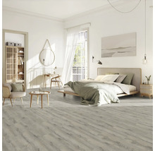 Heller Schlafzimmerraum mit Bett, Stuhl, Tisch und Laminatboden in Holzoptik.