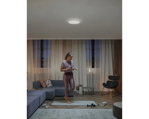 Frau beim Sport im Wohnzimmer mit Deckenleuchte