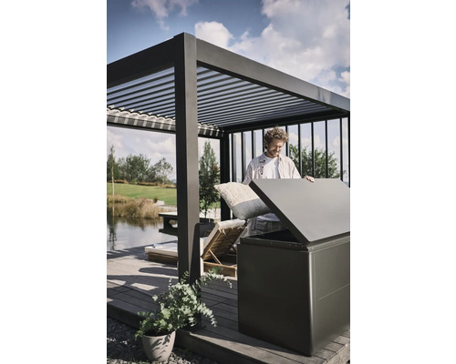 Mann verstaut Kissen in einer Aufbewahrungsbox im Außenbereich unter einer Pergola.