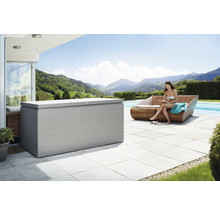 Szene im Freien mit einer großen Aufbewahrungsbox neben einer sitzenden Frau auf einem Sofa am Pool, mit Blick auf eine bergige Landschaft