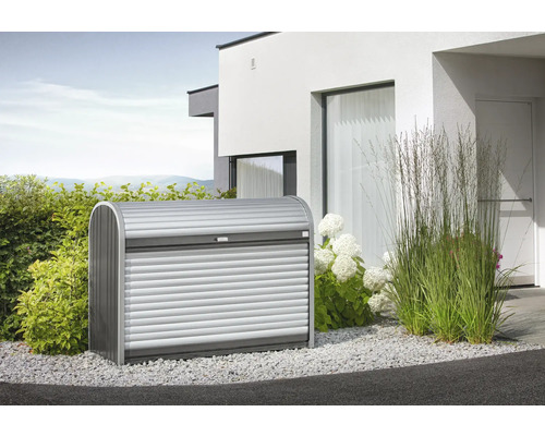 Mülltonnenbox Biohort Store Max 160 163x78x120 cm silber-quarzgrau Gartentruhe aus Metall mit Rollladen vor einem modernen Haus