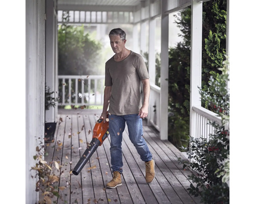 Mann reinigt Terrasse mit einem Laubbläser