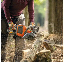 Eine Person sägt mit einer Husqvarna Kettensäge einen Baumstamm.