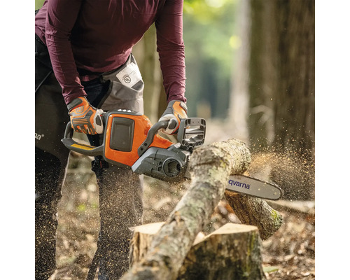 Eine Person sägt mit einer Husqvarna Kettensäge einen Baumstamm.
