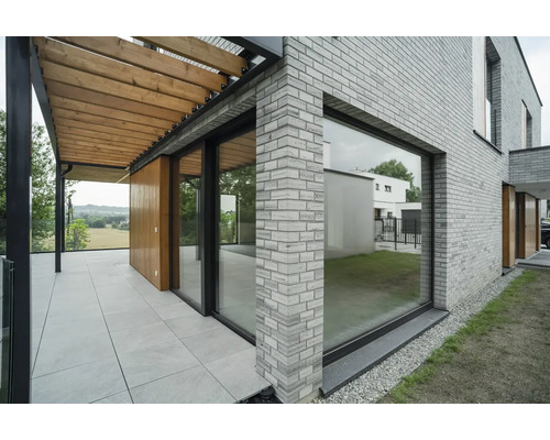 Außenansicht eines Hauses mit Ziegelmauerwerk, Terrasse und Pergola