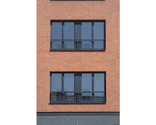 Fassade eines Hauses mit Ziegelmauerwerk und Fenstern mit Geländer